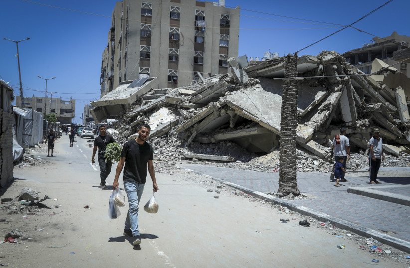 People walk next to the Hamad Towers, north of Khan Yunis in the southern Gaza Strip, which were destroyed by the Israeli military during the war in the Gaza Strip, June 26, 2026.