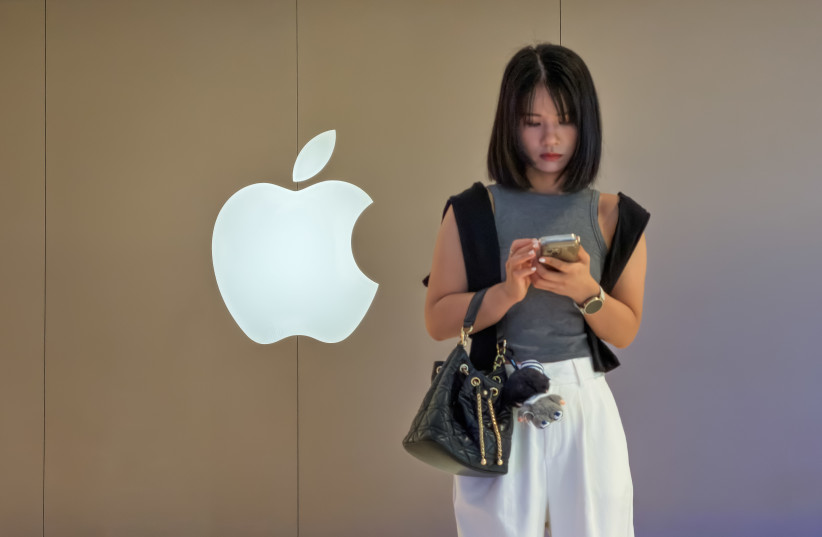 A woman uses a smartphone outside an Apple Store on June 20, 2026, in Shenzhen, Guangdong Province, China. Apple continues to expand its retail presence in China, one of the company's most important international markets, where smartphones, computers, wearable devices and digital services remain key