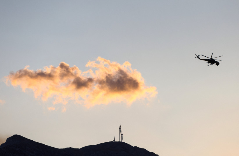 A firefighting helicopter flies over a wildfire burning next to the village of Krya Vrysi on the island of Crete, Greece, July 29, 2026.