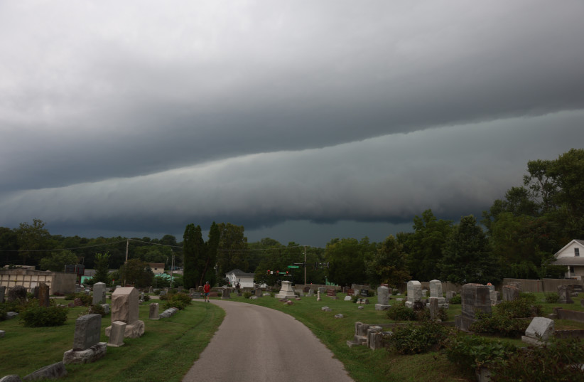 A person walks through Rose Hill Cemetery as a shelf cloud approaches behind them ahead of a severe thunderstorm on August 11, 2026, in Bloomington, Indiana. The storm was part of a widespread cluster of pop-up thunderstorms that developed across several Midwestern states.