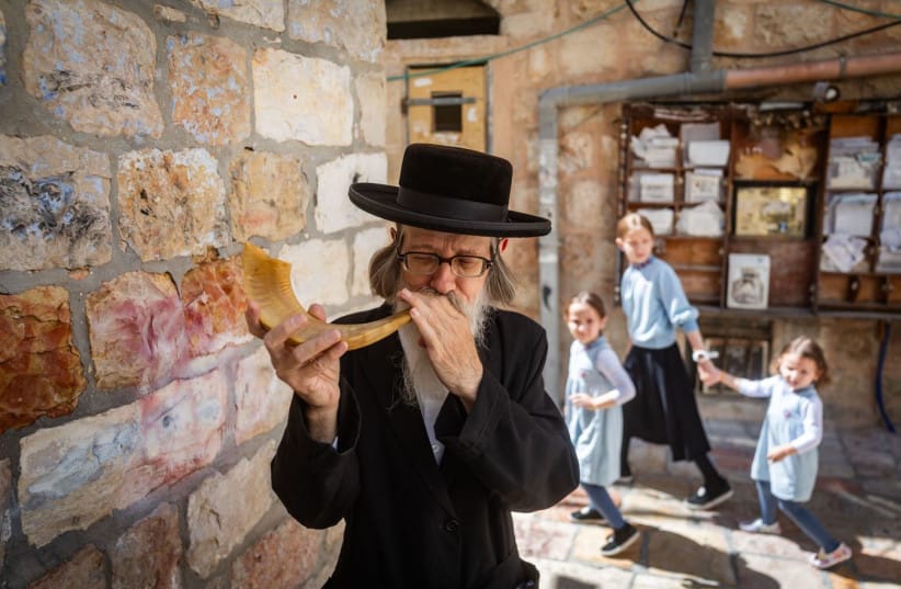 An ultra-Orthodox man blows a shofar ahead of Rosh Hashanah in Meah She’arim in Jerusalem in August