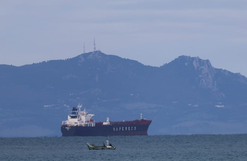 A Moroccan fisherman sails next to an oil tanker crossing the Strait of Gibraltar with the Atlas Mountains in the background, near the Spanish town of Tarifa, as seen from Tangier, Morocco, January 8, 2026.