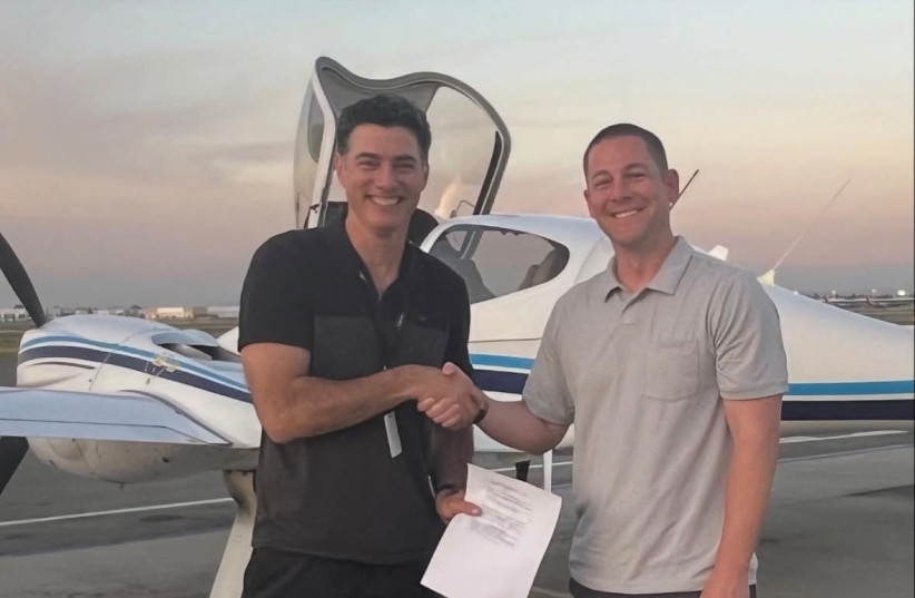 Guy Kapolnik (left) with a multi-engine aircraft in the background.