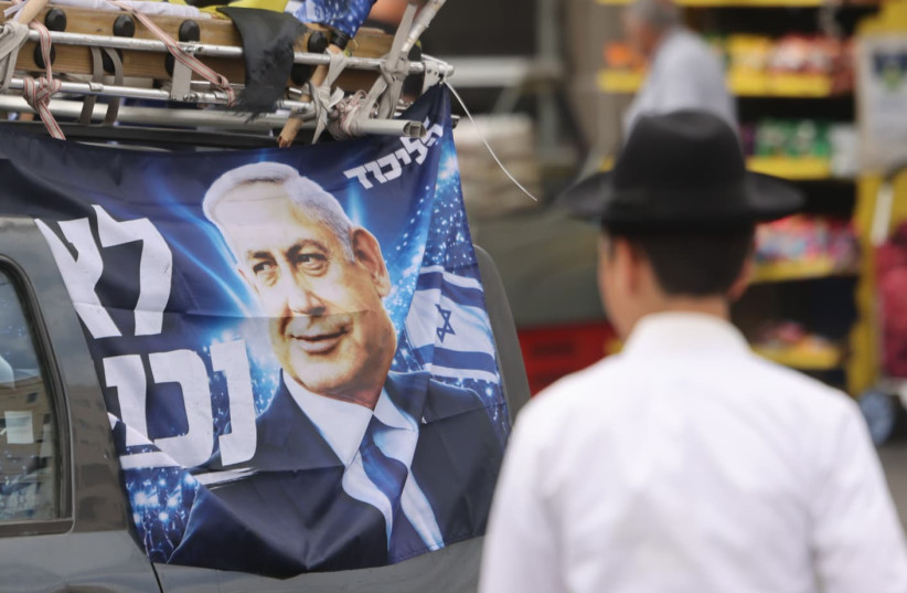 People walk past a vehicle displaying Likud campaign posters featuring Prime Minister Benjamin Netanyahu, in Jerusalem's Mahane Yehuda market, October 16, 2026