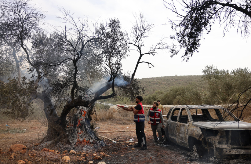Palestinian volunteers douse an olive tree set alight along with a Palestinian-owned vehicle, reportedly by Israeli settlers, near the village of Turmus Ayya, north of the city of Ramallah, in the West Bank on October 16, 2026.