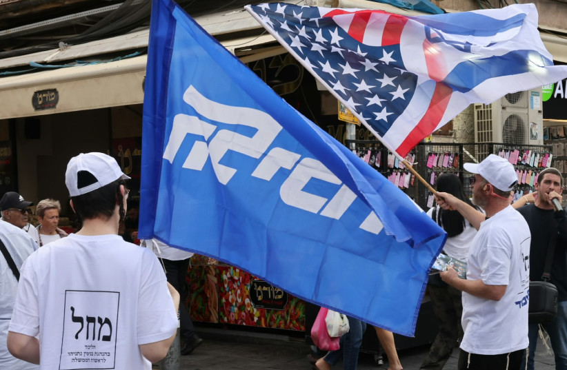 Likud activists hold the party's flag along with a hybrid Israeli-American flag, in the Mahane Yehuda market in Jerusalem, October 19, 2026