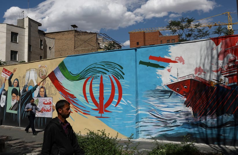 People walk on a street near a mural featuring an image of the late Supreme Leader of Iran, Ayatollah Ali Khamenei, in Tehran, Iran, May 18, 2026.