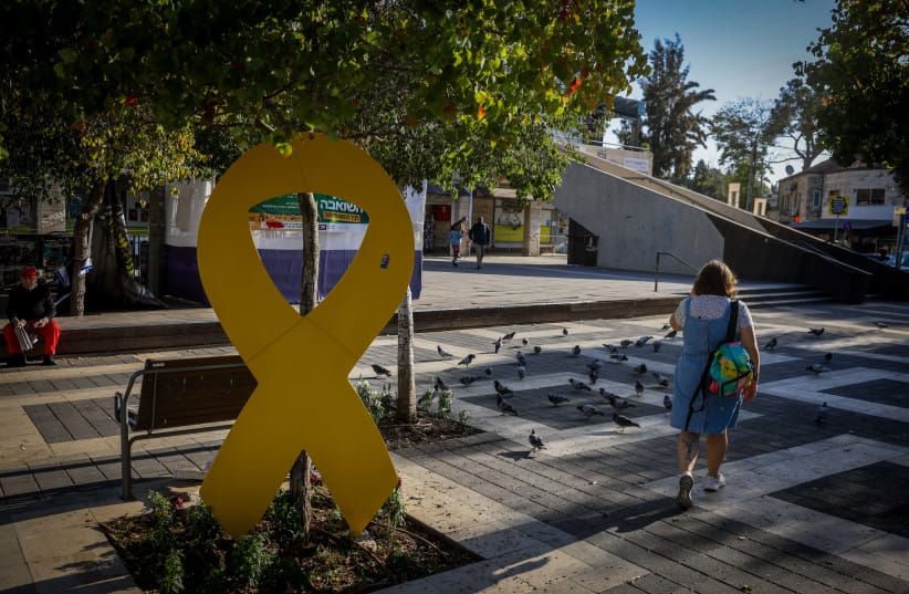 People walk next to a yellow ribbon that symbolises solidarity with the Israeli hostages in the Gaza Strip, in Jerusalem, October 27, 2024. (Illustrative)