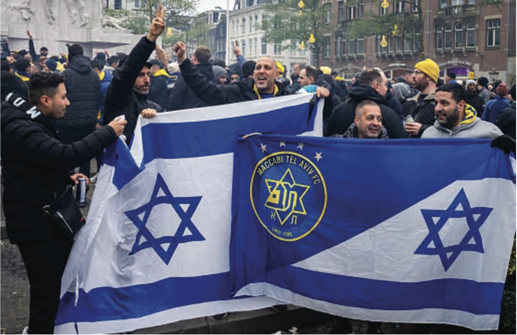 Supporters of Maccabi Tel Aviv hold flags at Dam Square ahead of the Europa League football match between Ajax and Maccabi Tel Aviv, in Amsterdam on  November 7, 2024 (photo credit: JEROEN JUMELET/ANP/AFP via Getty Images)