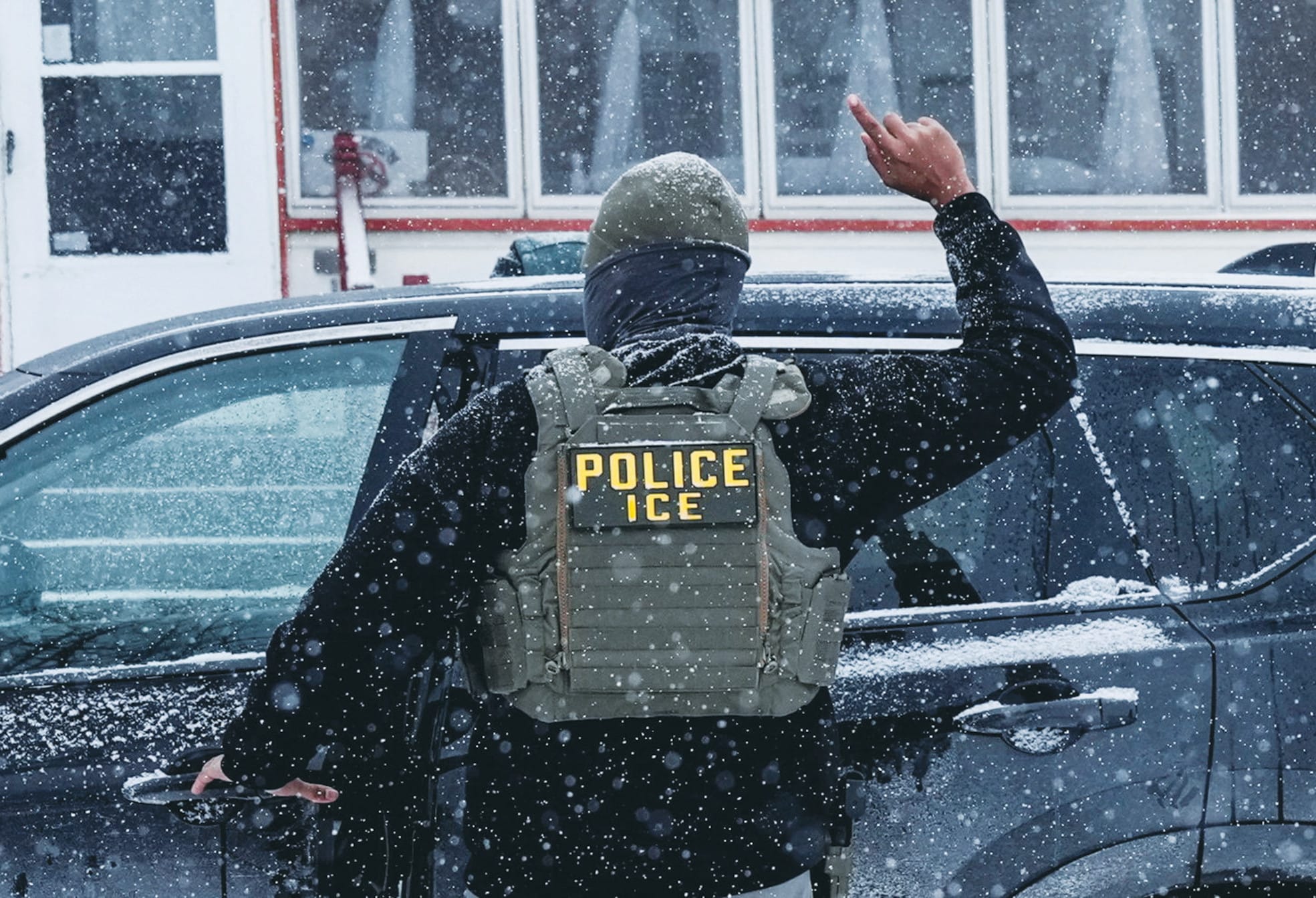 An immigration and Customs Enforcement (ICE) agent raises a finger moments after detaining a man during an immigration raid, on Sunday in Minneapolis. (photo credit: LEAH MILLIS/REUTERS)