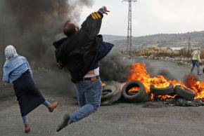 Palestinians throw stones at Israeli soldiers at a riot near Ramallah, December 2017