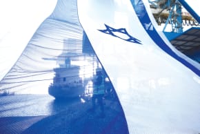 A WORKER at the sea port of Ashdod coordinates a crane to hang a giant Israeli national flag ahead of Remembrance Day.
