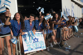  YOUNG ISRAELIS welcome new immigrants at Ben-Gurion Airport. Most Israelis, whether secular or religious, believe the country must have historical and spiritual continuity, says the writer.