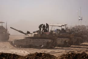 Israeli soldiers stand atop military vehicles as seen from the Israeli side of the Gaza border, August 18, 2025