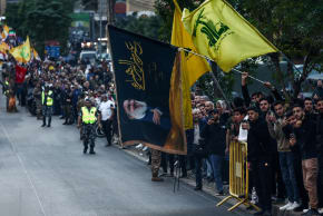 A person holds a flag with an image of late Hezbollah leader Hassan Nasrallah, as people wait for the arrival of Pope Leo XIV, during his first apostolic journey, in Beirut, Lebanon, November 30, 2025. 
