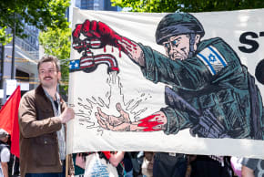 A protester holds a banner depicting an IDF soldier on January 11, 2026 in Melbourne, Australia. People gathered in Melbourne to protest Israeli President Isaac Herzog's planned visit to Australia.