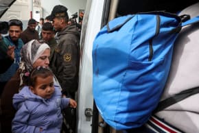 A woman carrying a child boards a bus as Palestinians get ready to leave Gaza for treatment abroad through the Rafah border crossing between Gaza and Egypt, February 2, 2026.