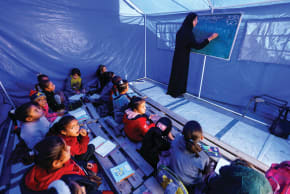 PALESTINIAN CHILDREN study inside a tent in the northern Gaza Strip. Education reform is critical to rebuilding Gaza, the writer says.