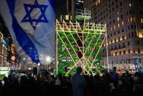 A crowd of people observe the lighting of the world’s largest Hanukkah menorah near Grand Army Plaza in New York City. 