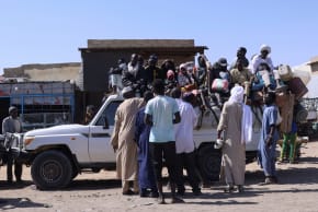 People sit on a pickup truck as they prepare to travel about 250 km south to Adre, on the Chad-Sudan border, at a transport station in Tine, eastern Chad, November 25, 2025. The movement comes amid the ongoing conflict between the paramilitary Rapid Support Forces (RSF) and the Sudanese army.