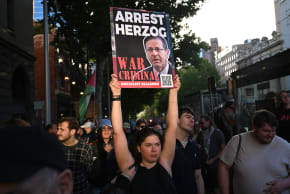A protester holds aloft a placard as they march during the visit of Israel's President Isaac Herzog in Melbourne on February 12, 2026