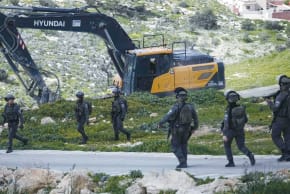 Las fuerzas de seguridad israelíes vigilan mientras unas excavadoras derriban un edificio palestino en Cisjordania, el miércoles. 