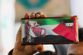 A protester holds a mobile phone with a Palestinian flag and a photo of slain Hamas spokesman Abu Obeidah, during a rally held by Houthi protesters to show solidarity with Palestinians in the Gaza Strip, in Sanaa, Yemen, August 30, 2024