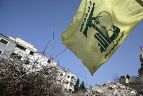 A flag of the Lebanese Shiite movement Hezbollah flutters above the rubble of a building that was hit in January by an Israeli strike in the southern Lebanese village of Qannarit, on February 16, 2026.