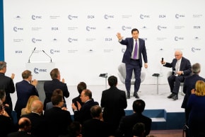 US Secretary of State Marco Rubio waves, next to Chairman of the Munich Security Conference Wolfgang Ischinger, as he gets a standing ovation after his speech at the Munich Security Conference in Munich, Germany, Saturday, Feb. 14, 2026.