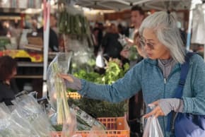 Una mujer eligiendo productos en un mercado.