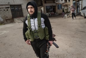 A Syrian man takes up arms at a gasoline station in a frontline village on January 23, 2026 in Sweida, Syria.