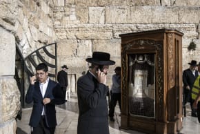 Ultra-orthodox Jewish men talk on the phone in front of the Western Wall in Jerusalem's Old City on December 4, 2025.