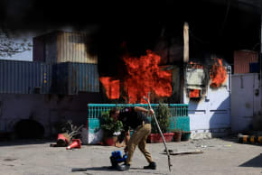 A police officer retrives items in front of a police checkpost burned by protesters near the US Consulate General, following news of US and Israeli strikes on Iran that killed former supreme leader Ayatollah Ali Khamenei, in Karachi, Pakistan March 1, 2026. 