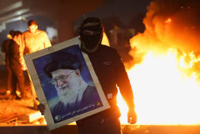 A protester holds an image of Iran's Supreme Leader Ayatollah Ali Khamenei as supporters of Iraqi Shi'ite armed groups attempt to move toward the US embassy located in Baghdad's Green Zone, while riot police deploy to block their advance, in Baghdad, Iraq, March 1, 2026.
