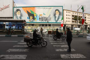 People drive by a mural featuring images of Iran's late Supreme Leader Ayatollah Ali Khamenei and the leader of Iran's 1979 Islamic Revolution, Ayatollah Ruhollah Khomeini on a building, in Tehran, Iran, March 2, 2026.