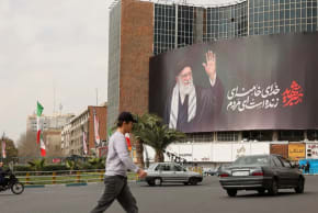 La gente camina cerca de una valla publicitaria del difunto líder supremo de Irán, el ayatolá Alí Jamenei, en una calle, después de que fuera asesinado en los ataques israelíes y estadounidenses del sábado, en Teherán, Irán, el 2 de marzo de 2026. 