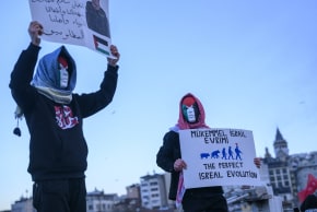 Masked demonstrators hold placards during a pro-Palestinian rally, reflecting the polarized regional reactions to the Israeli-US strike on Iran.