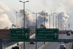 Motorists drive along an expressway as plumes of smoke rise after a strike in Tehran on March 5, 2026.