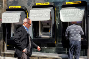 A man walks past another using an ATM machine of Iran's Melli Bank in Tehran on February 21, 2026; illustrative.