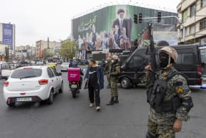 A police officer stands guard beneath a poster of Iran's former leader, Ayatollah Ali Khamenei on March 10, 2026 in Tehran, Iran.