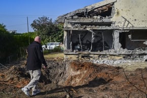 People stand at the scene where a house was hit by a Hezbollah missile fired toward central Israel, March 12, 2026