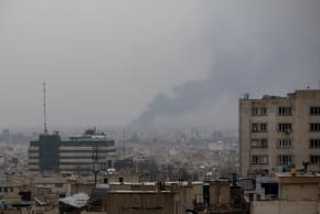 Smoke rises in the distance following an airstrike at the same time a Quds Day demonstration takes place on March 13, 2026 in Tehran, Iran.