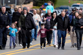 Parents are escorted by police down Walnut Lake Road back to their cars after being reunited with their children after a suspect crashed his truck into the hallway of Temple Israel synagogue in West Bloomfield, Michigan, U.S., March 12, 2026