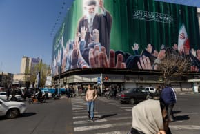 Pedestrians pass in front of a billboard featuring an image of Ayatollah Ali Khamenei on March 4, 2026 in Tehran, Iran; illustrative.