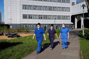 PEOPLE WEARING medical scrubs and face masks walk across campus at the University of Kent in Canterbury, south-east England on March 18, 2026, following an outbreak of meningitis.
