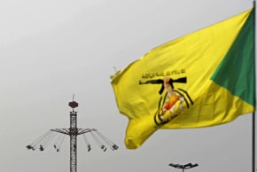 A flag of Iraq's pro-Iran paramilitary group Hezbollah Brigades (Kataib Hezbollah), flutters against the backdrop of people taking a swing ride at an amusement park during Eid al-Fitr celebrations, marking the end of the Muslim holy fasting month of Ramadan, in Baghdad on March 21, 2026.