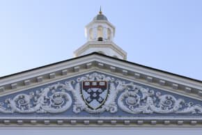 The Harvard University Coat of arms (Ve Ri Tas) is displayed on the front of the Harvard Business School building on October 25, 2025 in Boston, Massachusetts.