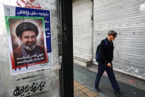 A man walks next to a poster with a picture of Iran's new Supreme Leader, Mojtaba Khamenei in Tehran, Iran, March 22, 2026