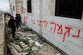Boys stand near graffiti, which Palestinians say was written by Israeli settlers, near Hebron.