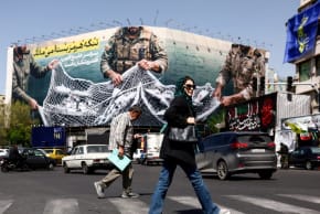 Varios transeúntes caminan por una calle, cerca de una valla publicitaria contra Estados Unidos, en medio del conflicto entre Estados Unidos e Israel con Irán, en Teherán (Irán), el 5 de abril de 2026.